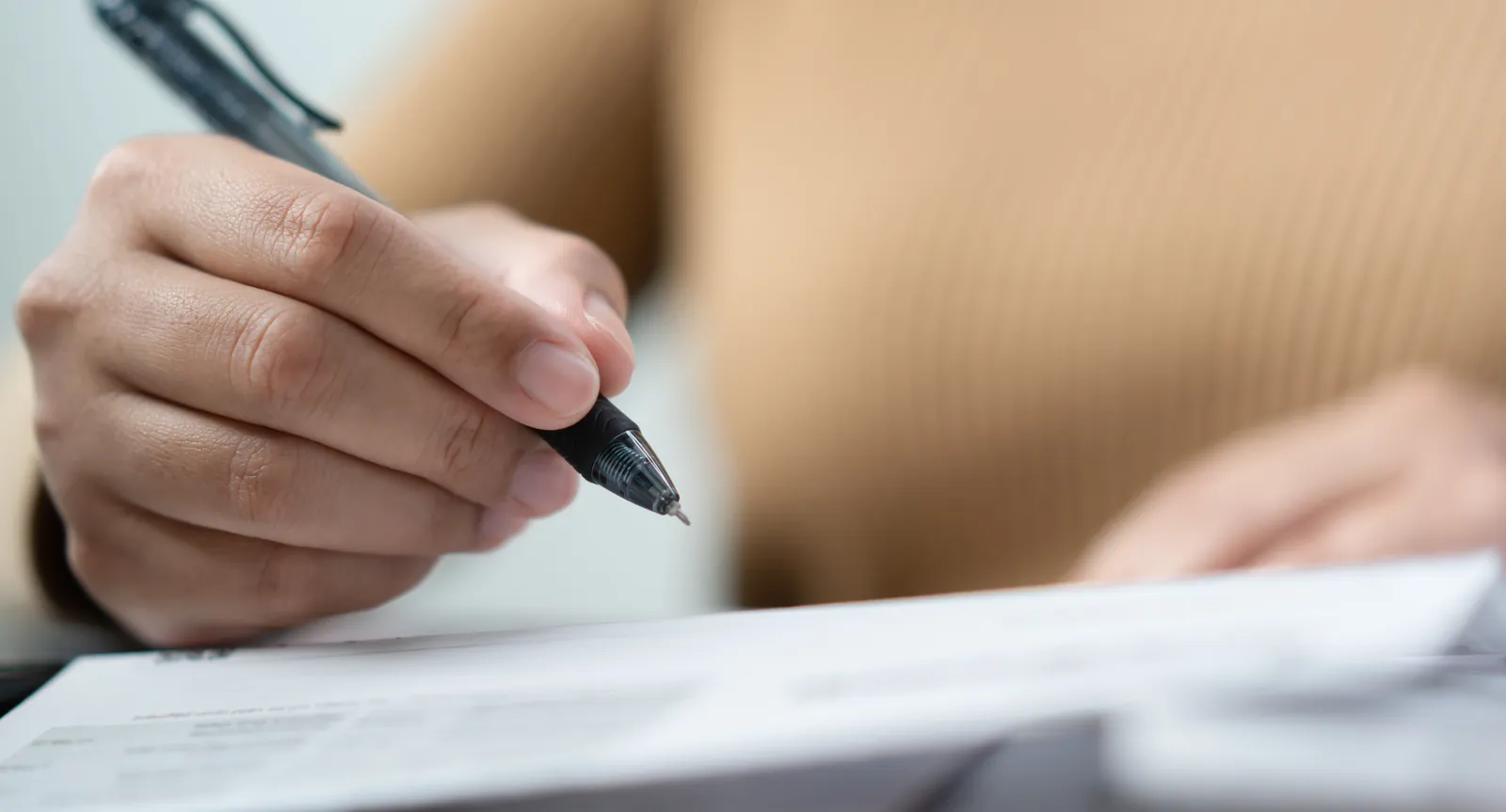 Person writing on paper with a pen